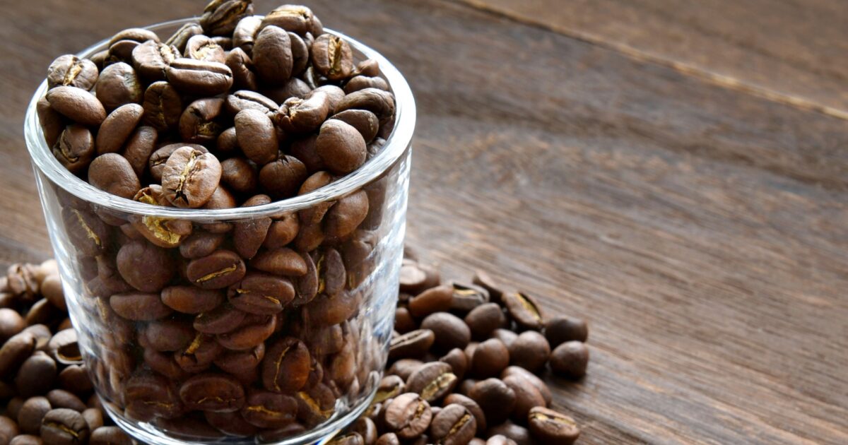 ガラスカップに入ったコーヒー豆と木製テーブル