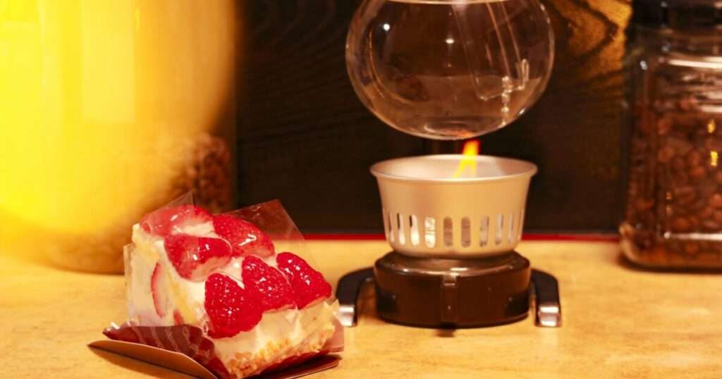 サイフォンで加熱中のコーヒーと苺のケーキ