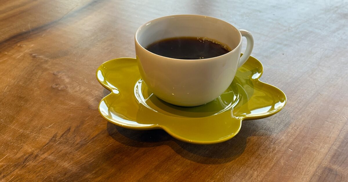 花形の緑色ソーサーに乗った白いカップのコーヒー