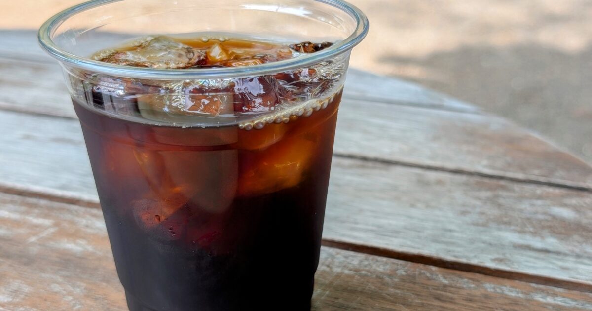 屋外テーブルに置かれたプラスチックカップのアイスコーヒー