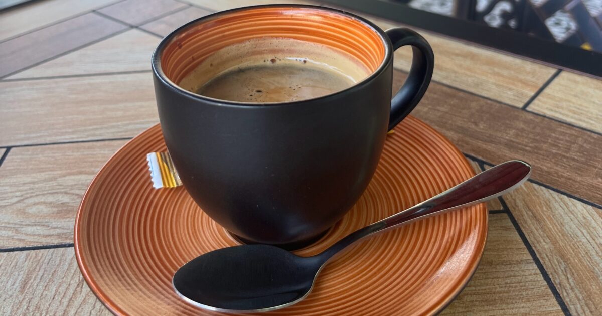 テラス席のテーブルに置かれた黒いマグのコーヒー