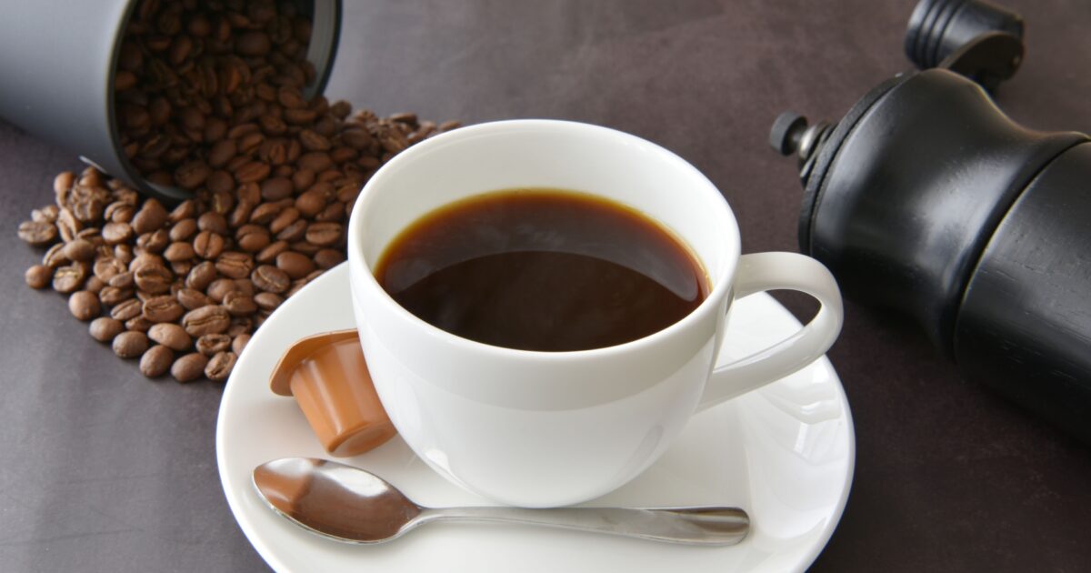 コーヒー豆とミルと白いカップコーヒーの組み合わせ