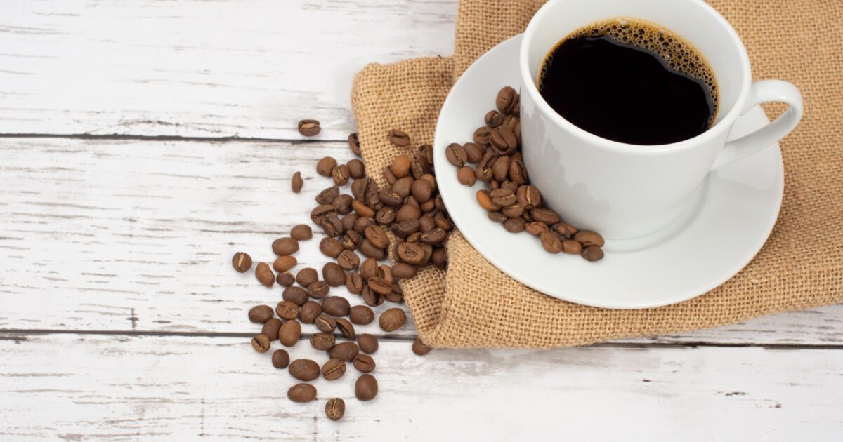 コーヒーカップと広がるコーヒー豆
